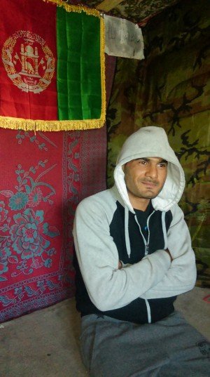 O afegão Ibrahim (ou Rachid) dentro da tenda-restaurante Chicken & Soup, com a bandeira afegã ao fundo