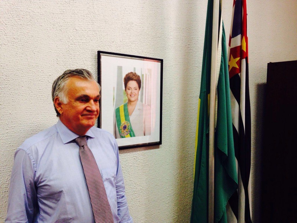 Juca Ferreira posa diante da fotografia oficial da chefa, na sede paulistana da Funarte - foto Jotabê Medeiros