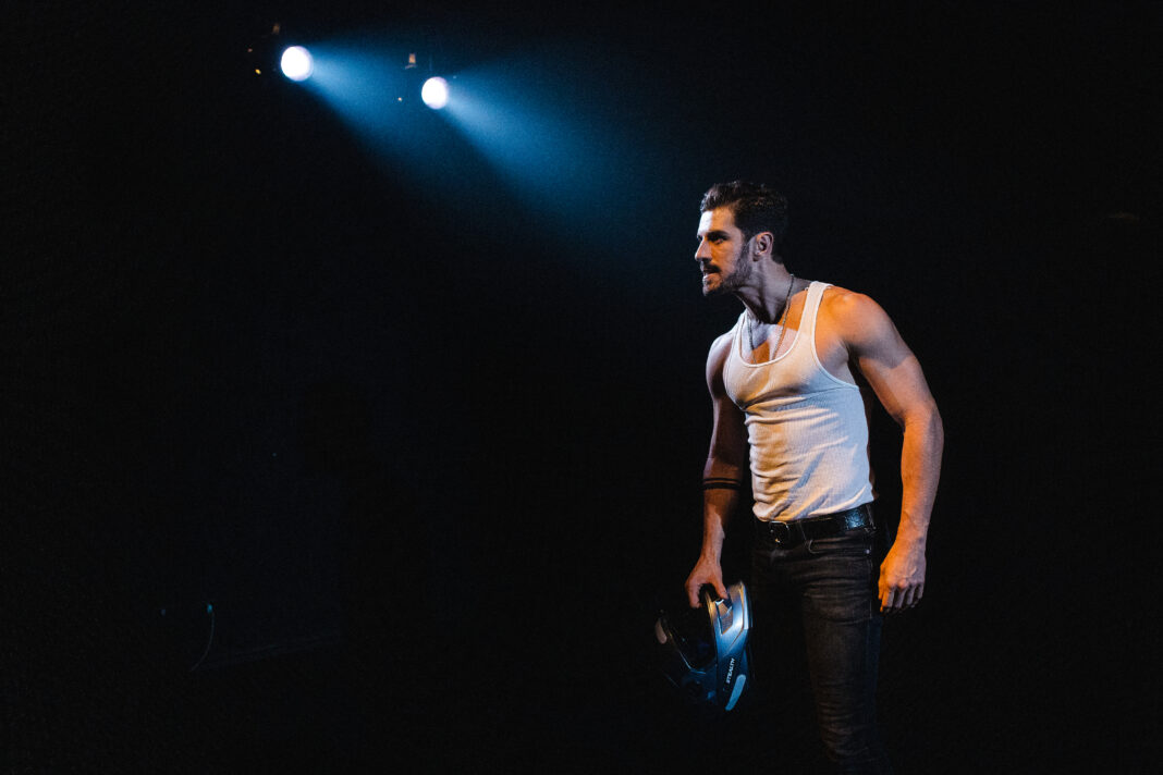 IMG_7938 O ator Robson Torinni encena o monólogo "Tráfico", em cartaz em São Paulo> Ele está vestido com uma camiseta brancas sem mangas e tem um olhar distante com uma luz cortante sobre sua cabeça.