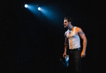 ‘Tráfico’, a sinfonia agridoce da exclusão O ator Robson Torinni encena o monólogo "Tráfico", em cartaz em São Paulo> Ele está vestido com uma camiseta brancas sem mangas e tem um olhar distante com uma luz cortante sobre sua cabeça.